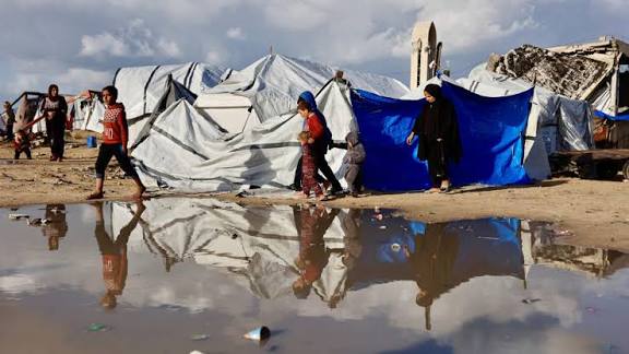 Displaced Palestinian families living in damaged tents and debris in Gaza during heavy winter rain and cold.